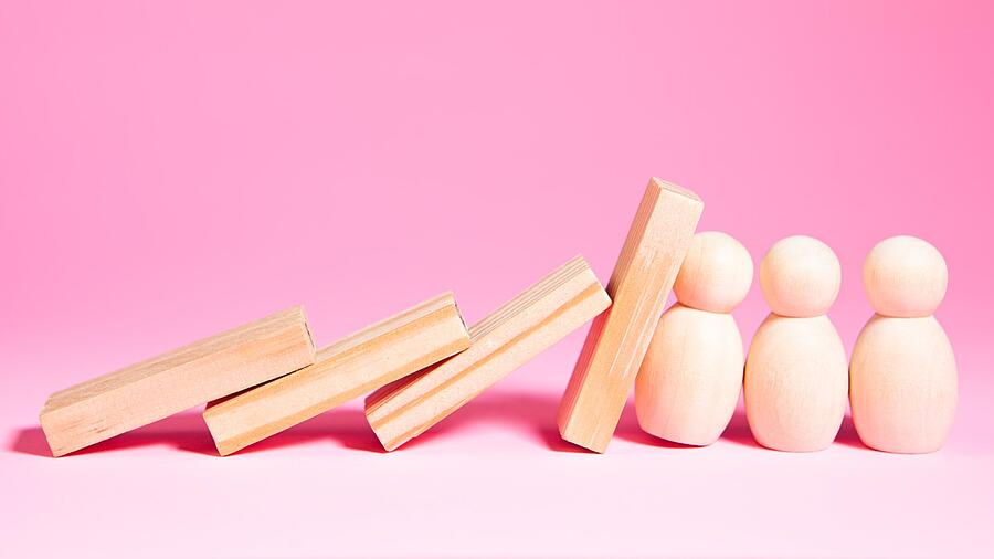 Holzspielzeugsteine, die fallen und eine Kettenreaktion auslösen. Frei Holzfiguren stoppen den Fall.