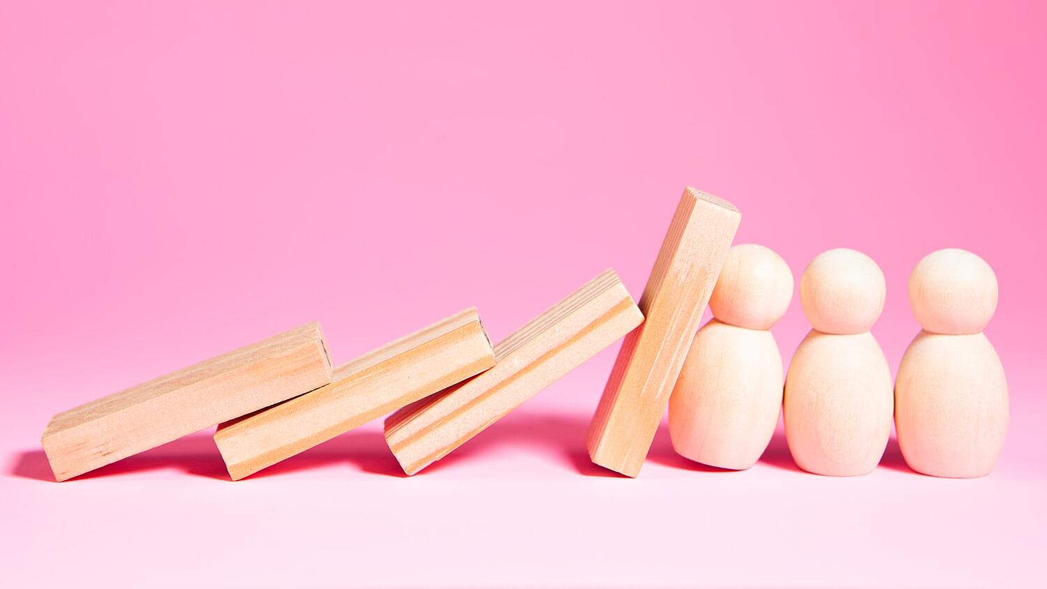 Holzspielzeugsteine, die fallen und eine Kettenreaktion auslösen. Frei Holzfiguren stoppen den Fall.