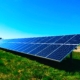 Foto einer großen Solaranlage, die auf einer Grünfläche steht. Es ist bestes Wetter, der Himmel ist kräftig blau