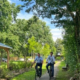 Zwei Radfahrer kommen auf den Betrachter zu, umgeben von Bäumen und Grünflächen. Die Radfahrer sind WFG-Geschäftsführer Kai Lass und Zukunftsmanager Joschka Weidemann