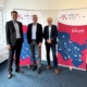 Drei Männer in Anzügen stehen vor zwei Roll-ups des Verbands der Wirtschaftsförderungen in Schleswig-Holstein